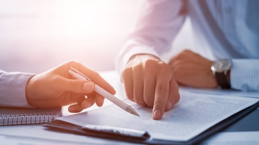 Human hands working with documents at desk and discussing an Aetna insurance contract