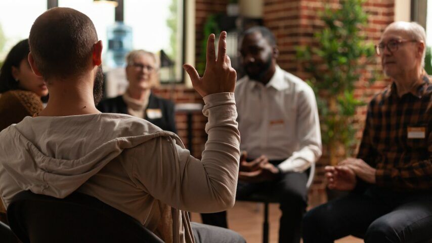 Man with addiction sharing health problems with group at aa meeting, talking to therapist in Ohio